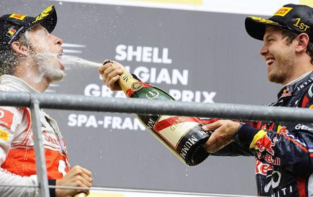 Sebastian Vettel poi Jensona Buttona szampanem na podium GP Belgii /AFP