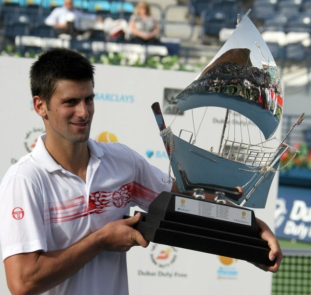 Novak Djokovic prezentuje efektowne trofeum za zwycięstwo w Dubaju /AFP