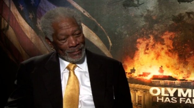 Morgan Freeman opowiada o pracy przy filmie „Olimp w ogniu”. Bohaterem tego thrillera jest Mike Banning (Gerard Butler), agent Super Service dbający o bezpieczeństwo prezydenta Stanów Zjednoczonych (Aaron Eckhart). Na skutek nieodpowiedzialnego zachowania zostaje zwolniony i rozpoczyna pracę jako ochroniarz w supermarkecie. Tymczasem prezydent, odwołując planowaną inwazję na Koreę Północną, rozwściecza ekstremistę Kanga (Rick Yune), który postanawia wymóc na głowie państwa zmianę decyzji. Wraz z grupką osób o bliskich mu poglądach politycznych przeprowadza atak na Biały Dom, biorąc prezydenta i pracowników za zakładników. W tej sytuacji na pomoc zostaje wezwany Banning, który jako jedyny może uratować uwięzionych ludzi, zapobiec międzynarodowej katastrofie i przywrócić swoje dobre imię.