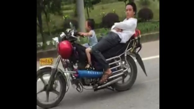 Czteroletni chłopiec prowadzi motocykl, podczas gdy jego tata wygodnie mości się na miejscu dla pasażera. Szokujące wideo nagrano w Zhanjiang w Chinach. 