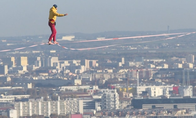 Usytuowany na 150 m nad ziemią mężczyzna przeciwstawia się grawitacji, aby zachować równowagę na drucie rozciągniętym między dwoma wieżowcami. 
