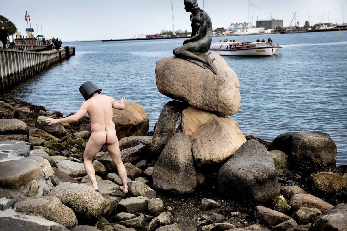 Dokładnie 50 lat temu, ku wielkiemu zaskoczeniu turystów i samych Duńczyków, ktoś obciął głowę Małej Syrence – pomnikowi, który stoi w Kopenhadze. Do dziś nie wiadomo, kto to zrobił. Do dziś też nie odnaleziono głowy syrenki. Aby przypomnieć o tym wydarzeniu, duński performer Uwe Max Jensen, pojawił się na Langelinie … nagi.