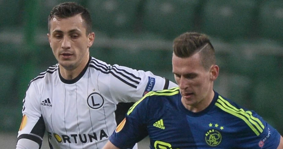 Arkadiusz Milik (P) z Ajaxu Amsterdam obok biegnącego Tomasza Jodłowca