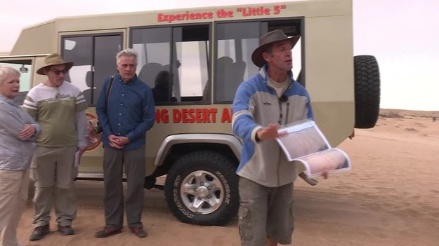 Chris Nel jak mało kto zna tajemnice Pustyni Namib. Ten przewodnik bez trudu znajduje pod piaskiem białą damę, wie gdzie chowają się przezroczyste gekony, wśród rzadkiej roślinności potrafi dostrzec kameleona. 


Zawsze podkreśla, że to bardzo delikatny ekosystem, któremu zagraża obecność samochodów i turystów. – Problem polega na tym, że te ślady pozostaną tu na zawsze, ponieważ Pustynia Namib to 30 procent piasku i 70 procent żwiru, czyli drobnych kamieni, których w przeciwieństwie do ziaren piasku, wiatr nie uniesie – tłumaczy przewodnik. 


To właśnie tu powstawały zdjęcia do hollywoodzkiej megaprodukcji „Mad Max: Na drodze gniewu”. Realizacja filmu wywołała skandal. Ekolodzy oskarżyli ekipę i producentów o zniszczenie całych połaci pustyni, zaliczanych do najstarszych na świecie. Chris Nel nie jest jednak aż tak radykalny w swojej ocenie. – Pracowali na niewielkim obszarze, a po zdjęciach, zgodnie z umową, oczyścili teren. Wysłali tam ludzi ze szczotkami, grabiami i wielkimi szczotkami. Tak wysprzątali, że niektóre miejsca wyglądają lepiej, niż przed ich przyjazdem – mówi Nel. 


