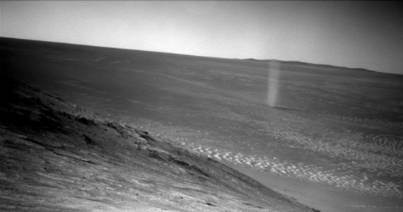 NASA opublikowała nowe zdjęcie wykonane przez swoje laboratorium na kółkach, Mars Exploration Rover Opportunity. Widać na nim miedzy innymi ślady łazika, wjeżdżającego na zbocze "Knudsen Ridge" w rejonie południowej krawędzi "Marathon Valley". To, co na tym zdjęciu najciekawsze, to widoczna w oddali pyłowa trąba powietrzna, tak zwany "dust devil", zjawisko często na Czerwonej Planecie obserwowane.