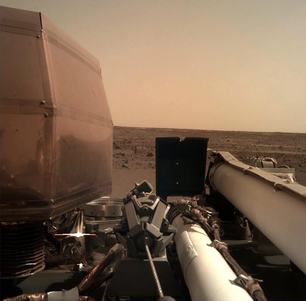 Sonda InSight "odpoczywa" na powierzchni Marsa po męczącej podróży i emocjonującym lądowaniu. Najnowsze laboratorium naukowe na Czerwonej Planecie rozłożyło już swoje baterie słoneczne, przesłało też pierwsze zdjęcie z kamery IDC (Instrument Deployment Camera). Obraz wykonany przez obiektyw przesłonięty jeszcze przezroczystą, przeciwpyłową osłoną przesłano za pośrednictwem krążącej na orbicie sondy Mars Odyssey.