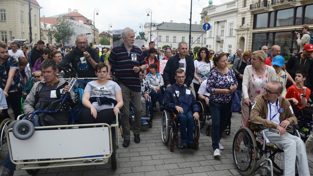 "Niepełnosprawni - pełnoprawni", "Każdy zasługuje na życie", "Weźcie nasz zasiłek i naszą niepełnosprawność", "Żądamy godnego życia" - pod takimi hasłami przed Pałacem Prezydenckim w Warszawie w samo południe rozpoczął się protest osób niepełnosprawnych i ich opiekunów. Po odczytaniu listu do prezydenta Andrzeja Dudy, protest przeniósł się przed kancelarię premiera, skąd zgromadzeni przeszli przed Sejm.