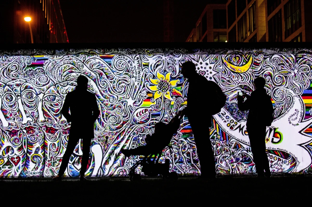 Na blisko 30 lat podzielił nie tylko miasto i państwo, ale też mentalność ludzi żyjących po jego obu stronach. Wraz z jego upadkiem 9 listopada 1989 roku zakończyła się zimna wojna i trwający od końca II wojny światowej podział Europy na aliancką i sowiecką strefę wpływów. Mur Berliński – bo o nim mowa – powstał, by powstrzymać emigrację ze wschodniej części Niemiec i samego Berlina do jego zachodniej, alianckiej zony. Od 13 sierpnia 1961 roku rozpoczął się podział miasta. Najpierw ustawiono zasieki z drutu kolczatego, potem wzniesiono sam mur. Ci, którzy próbowali go sforsować, ginęli. Sama próba przedostania się do zachodniej części miasta była przestępstwem. Mimo to przez Mur Berliński udało się uciec ponad 5 tysiącom obywateli NRD. I tak do historycznego przemówienia w czerwcu 1987 prezydenta Stanów Zjednoczonych Ronald Reagan przed Bramą Brandenburską, w którym zwracał się do ówczesnego przywódcy ZSRR: "Panie Gorbaczow, otwórz pan te bramę. Panie Gorbaczow, zburz pan ten mur". Dwa lata później 9 listopada przy Bornholmer Strasse otwarto pierwsze przejście graniczne między Wschodnim a Zachodnim Berlinem. W kierunku muru ruszyły tysiące berlińczyków…