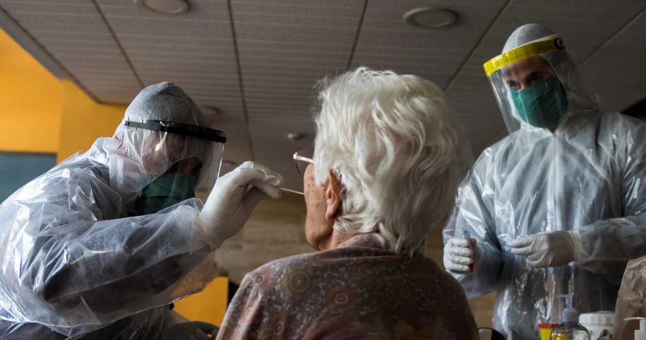 Pracownicy hiszpańskich służb sanitarnych pobierają wymaz u starszej kobiety