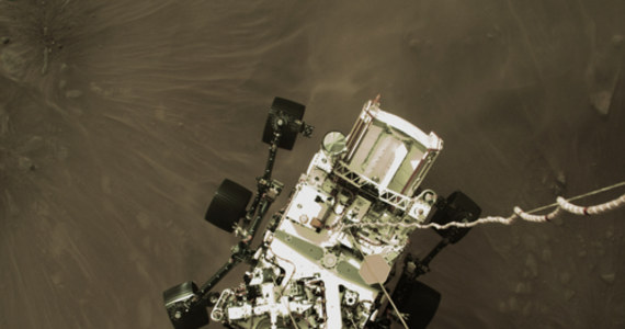 Dzień po lądowaniu na Marsie łazik Perseverance wydaje się być w idealnym stanie i przesyła z pomocą sond krążących wokół Czerwonej Planety pierwsze kolorowe zdjęcia. Szczególnie cenne jest to pokazujące, jak na linach zwisa z kosmicznego dźwigu tuż przed lądowaniem. NASA publikuje też czarno-białe zdjęcie wykonane w czasie manewru lądowania przez sondę Mars Reconnaissance Orbiter, na którym widać łązik opadający na spadochronie.