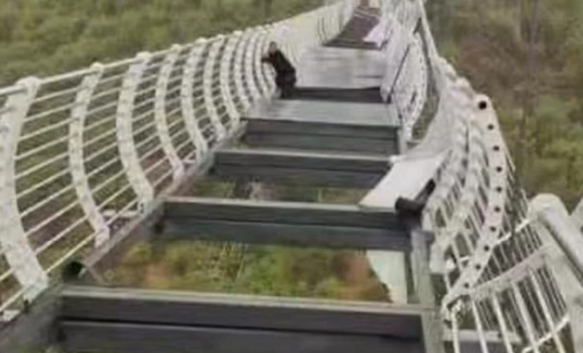 Na zdjęciu opublikowanym w przez oficjalną chińską agencję prasową Xinhua widać turystę kurczowo trzymającego się balustrady mostu, podczas gdy w naruszonej podłodze brakuje części dużych szklanych paneli.