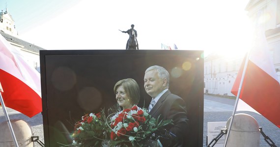 Naprzeciwko sceny przed Pałacem Prezydenckim powoli zbierają się mieszkańcy stolicy oraz odwiedzający Warszawę. Przed pałacem ustawiony jest portret śp. Lecha i Marii Kaczyńskich, którzy zginęli 12 lat temu w katastrofie smoleńskiej.