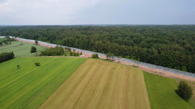 Zdjęcia z drona przedstawiające mur budowany przez Polskę na granicy z Białorusią. Mur o wysokości 5 metrów ma już 135 kilometrów. Całość granicy między obydwoma krajami to 180 kilometrów. Budowa ma zostać ukończona do końca czerwca. Również wtedy zostanie wyposażony w system kamer i czujników elektronicznych.