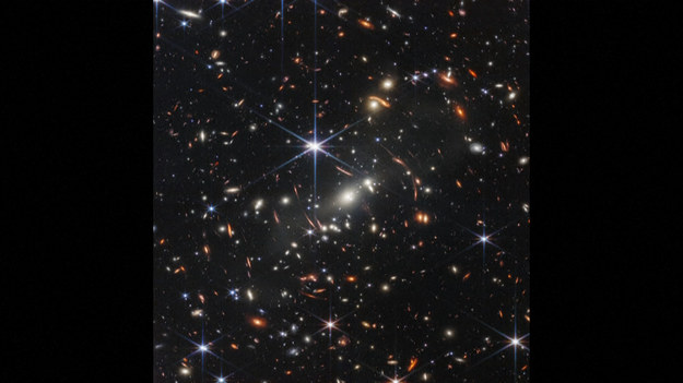 Prezydent USA Joe Biden odsłonił 11 lipca obecnego roku historyczne, pierwsze zdjęcie uchwycone przez Kosmiczny Teleskop Jamesa Webba, Obraz o wysokiej rozdzielczości ujawnia gromadę galaktyk SMACS 0723, tak jak wyglądała 4,6 mld lat temu. Pokazanie kosmosu w jego wyglądzie sprzed 13 mld lat było możliwe dzięki ogromnej masie tej gromady galaktyk, która posłużyła za tzw. soczewkę grawitacyjną. Kosmiczny Teleskop Jamesa Webba został wysłany w kosmos przez NASA 25 grudnia 2021 roku. Ma on kontynuować pracę Teleskopu Hubble’a.