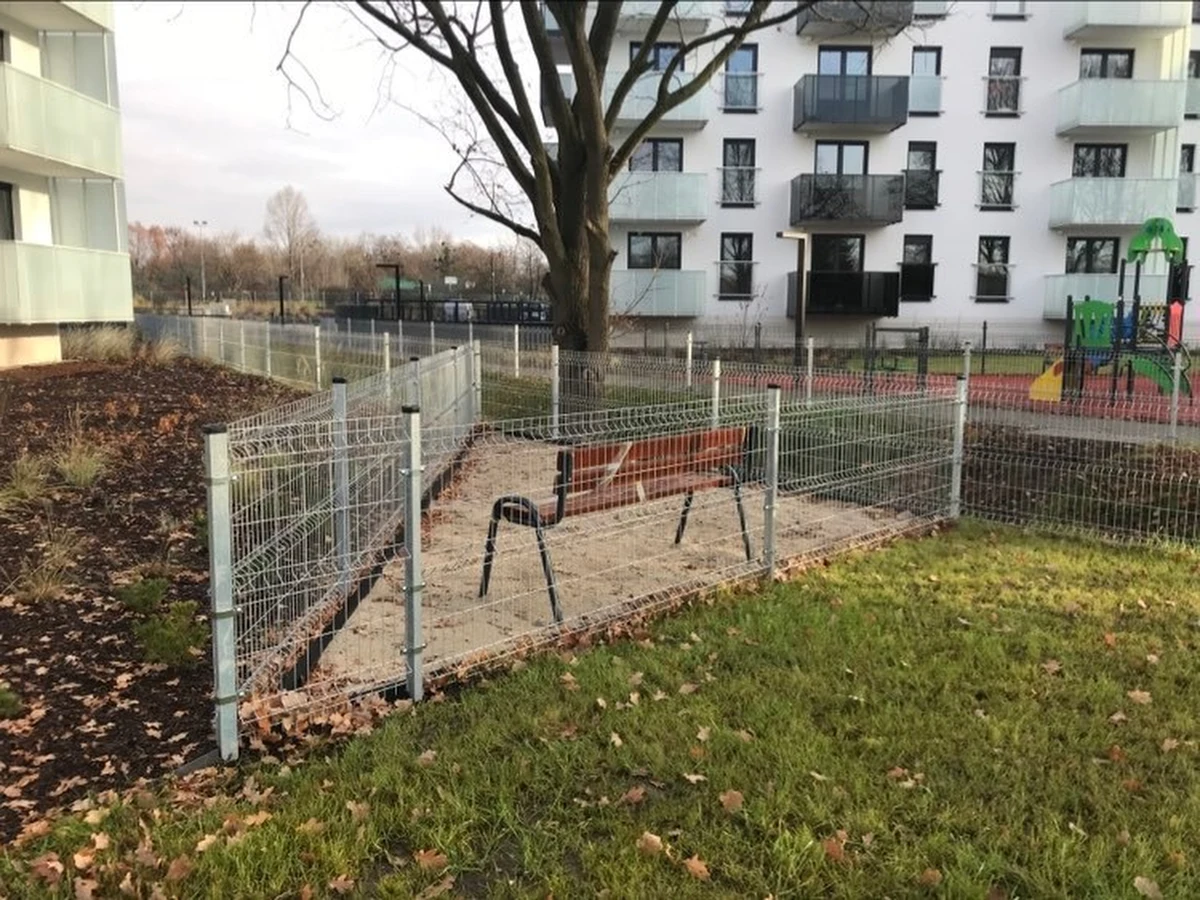 Przy nowych blokach na osiedlu Kuźniki we Wrocławiu stanęła ławka, o której zrobiło się głośno. Z samą ławką wszystko jest w porządku, ale jak zauważają mieszkańcy nie sposób na niej usiąść. Chyba, że przeskoczy się płot, którym ją ogrodzono. Deweloper uspokaja: to nie koniec prac.