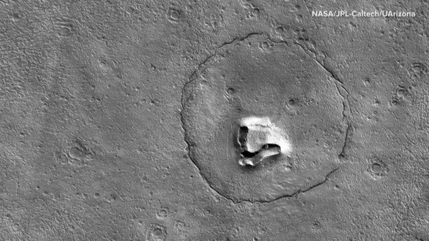 Od 2006 roku wokół Marsa krąży sonda badawcza Mars Reconnaissance Orbiter. Na jej pokładzie znajduje się m.in. zaawansowany sprzęt do obserwacji powierzchni naszego kosmicznego sąsiada. Do głównych zadań sondy należą badania atmosfery oraz historii ewolucji Marsa, ale również wytypowanie dogodnych miejsc dla przyszłych lądowań misji załogowych. Przy okazji, ziemski sprzęt optyczny może dostrzec kształty, które niekoniecznie kojarzą nam się z Marsem. Mowa tu o... misiach. Pod koniec grudnia naukowcy NASA wykonali zdjęcia formacji terenu, szerokiej na dwa kilometry, która przypomina uroczy pyszczek bohatera bajek dla dzieci.