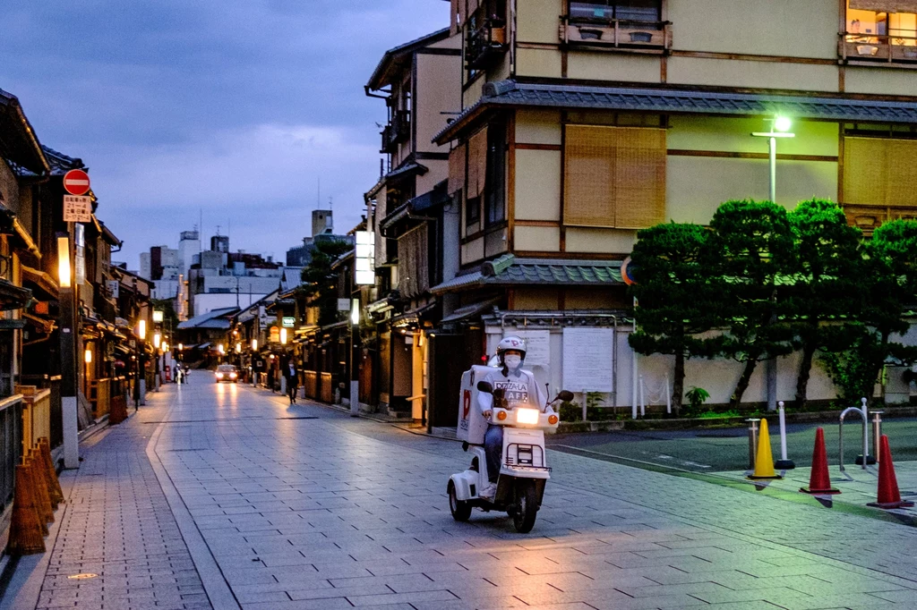 Motocyklista w dzielnicy Kioto - Gion. W tle widać tradycyjną niską zabudowę