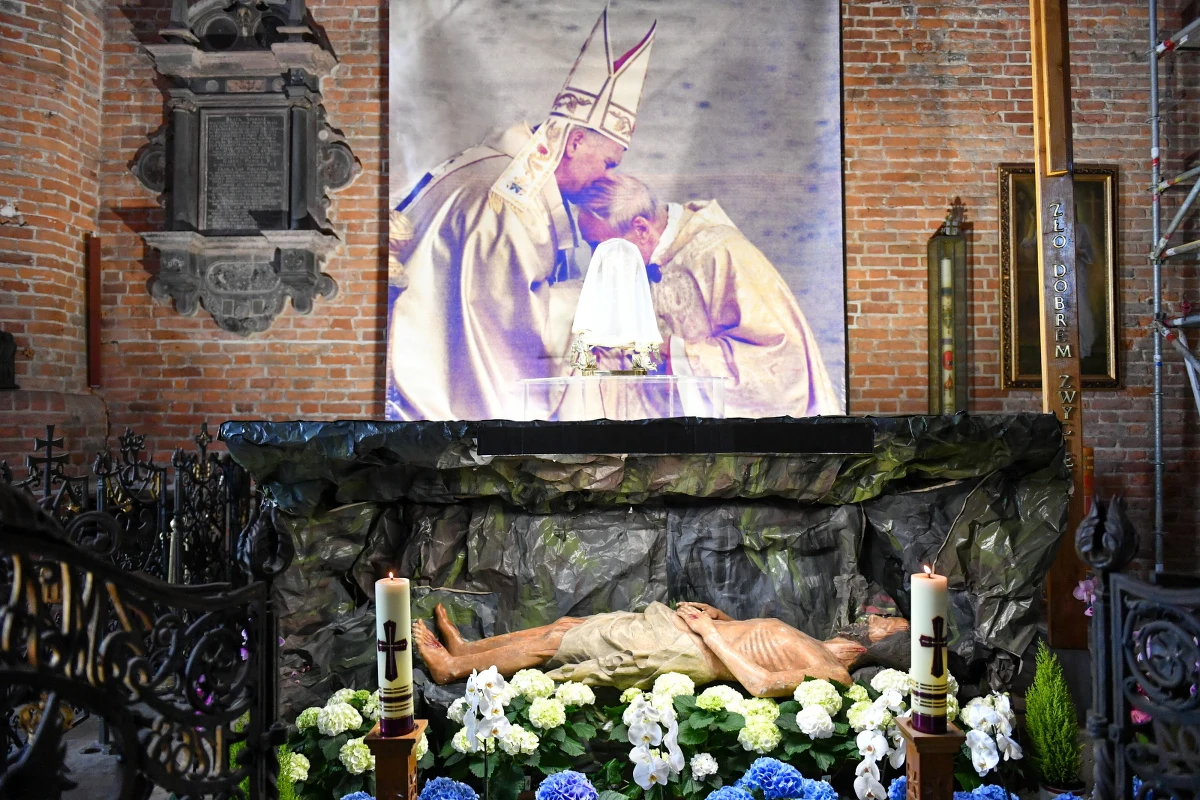 Archiwalne zdjęcie wykonane podczas inauguracji pontyfikatu Jana Pawła II, na którym widnieje papież i kardynał Stefan Wyszyński umieszczono przy grobie Pańskim w parafii pw. św. Brygidy w Gdańsku. Na zdjęciu widnieje napis: Idziemy za krzyżem, aby wygrać życie.