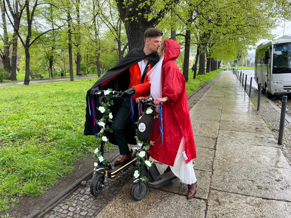 ​Niecodzienny wjazd na nową drogę życia we Wrocławiu. Para młoda pojechała tam dziś do ślubu... hulajnogami. W ślubnym orszaku nie zabrakło ich bliskich, oczywiście także na hulajnogach i rowerach. Nie przeszkodził im nawet deszcz.