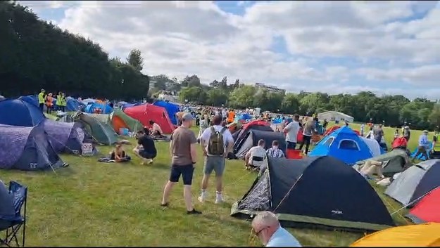 Polacy polują na bilety. "Będziemy stali tu całą noc"Całą grupą ruszyli na swój podbój Wimbledonu, czyli rozpoczęli w trybie "last minute" starania o wywalczenie biletów. Jak w ostatniej chwili zdobyć to dobro luksusowe, jeśli nie miało się szczęścia i, wzorem choćby mistrzostw świata w piłce nożnej, po uprzednim zarejestrowaniu się na dedykowanej platformie chętni nie znaleźli się w gronie wylosowanych?Krzysztof: - Miejsca w kolejce mamy już zajęte, tylko na chwilę byliśmy w samochodzie. Jeśli nie ma się szczęścia w losowaniu, to zostaje jeszcze taka szansa. Organizatorzy zawsze sprzedają po 500 biletów na kort centralny i kort numer jeden bodaj do wtorku drugiego tygodnia turnieju. A później już w ogóle nie można nawet w takim trybie nabyć wejściówek. Będziemy stali tu całą noc, a w poniedziałek rano uformuje się kolejka. Próbujemy na kort numer 1, na którym grać ma Iga.
