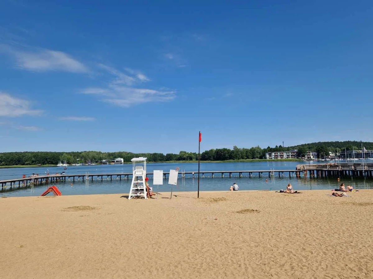 Zakaz kąpieli na kąpieliskach miejskich na jeziorze Ukiel w Olsztynie. Czerwona flaga powiewa tam z powodu podejrzenia zakwitu sinic.