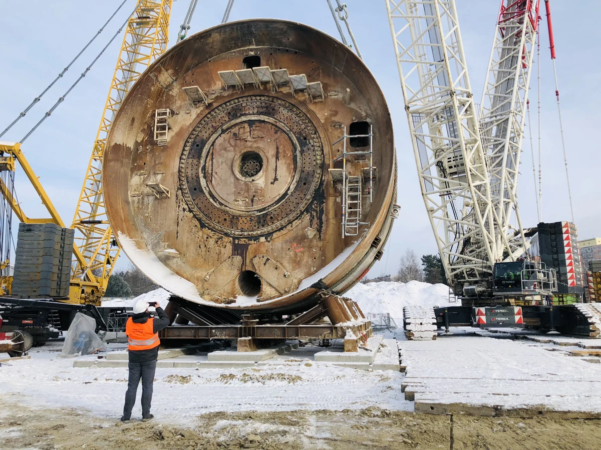 Niemal 9-metrowa tarcza TBM Faustyna wyszła na powierzchnię ziemi i czeka na przeniesienie na torami kolejowymi - tak wygląda kolejny etap budowy tunelu kolejowego, który połączy dworzec Łódź Fabryczna ze stacjami: Łódź Kaliska i Żabieniec. To będzie pierwsza tego typu operacja w Polsce. Tarcza ma być przeniesiona dziś w nocy.