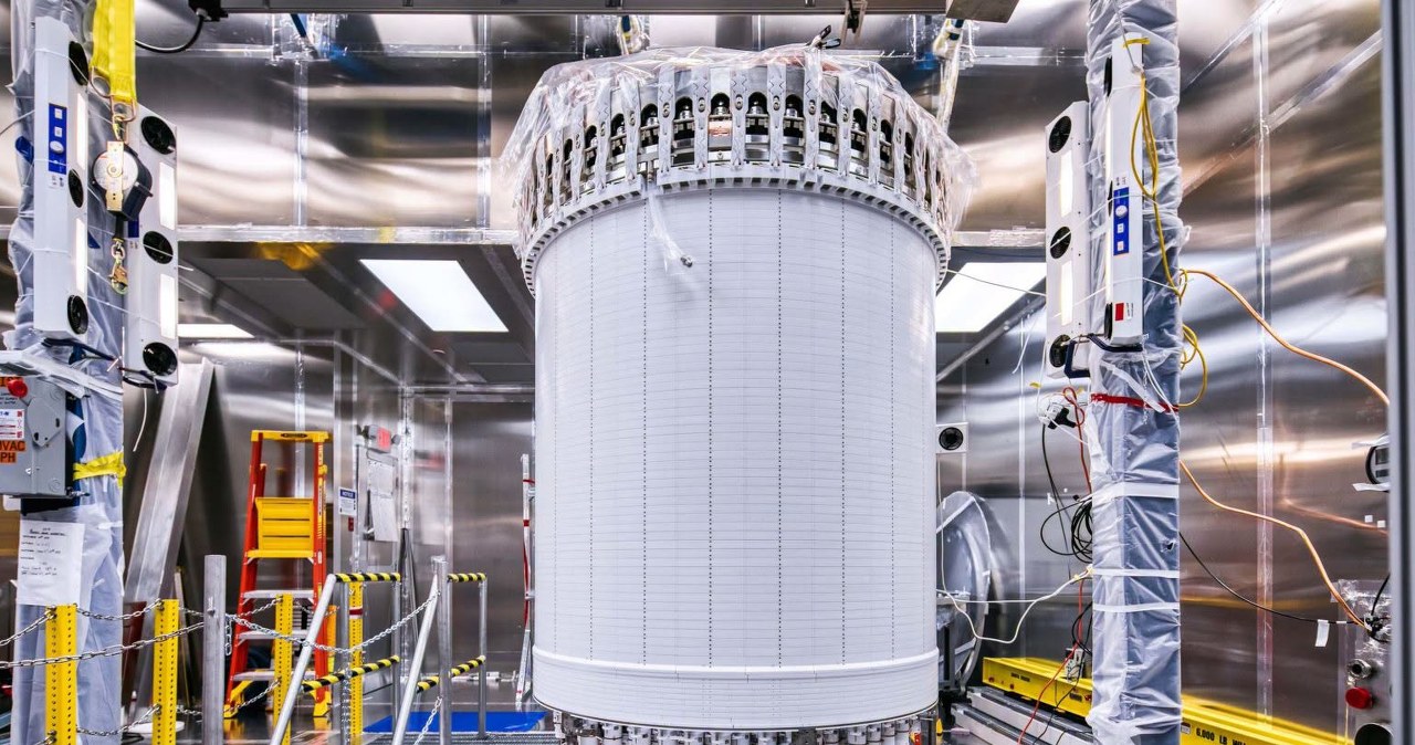 Cylindryczny detektor LUX-ZEPLIN w sterylnym laboratorium, otoczony sprzętem pomiarowym i kablami