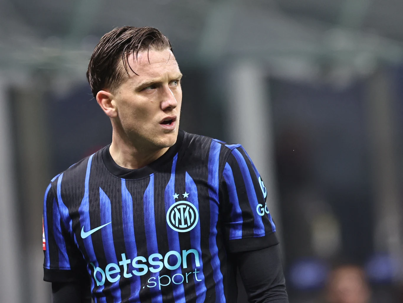 Piłkarz w niebiesko-czarnej koszulce Interu Mediolan, widoczny z wyraźnym wyrazem twarzy skupienia lub lekkiego zaskoczenia podczas meczu, tło stadionowe zamazane. Piłkarz w niebiesko-czarnej koszulce Interu Mediolan, widoczny z wyraźnym wyrazem twarzy skupienia lub lekkiego zaskoczenia podczas meczu, tło stadionowe zamazane.