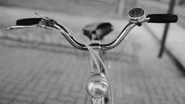 Kierownica roweru z dzwonkiem i przednią lampą ustawiona na tle brukowanej nawierzchni. Kierownica roweru z dzwonkiem i przednią lampą ustawiona na tle brukowanej nawierzchni.
