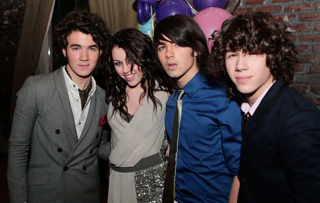 Miley Cyrus z braćmi Jonas. Nick pierwszy z prawej. Fot. Kevin Winter