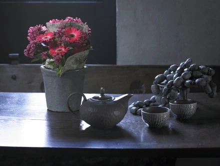 Styl klasyczny. Pieczennik, mini gerbera oraz cantedeskia. Razem z dzbankiem na herbatę kompozycja tworzy nowoczesną, martwą naturę. Kształt i kolor kwiatów zapewnia niezwykle wyraźny, klasyczny styl. 