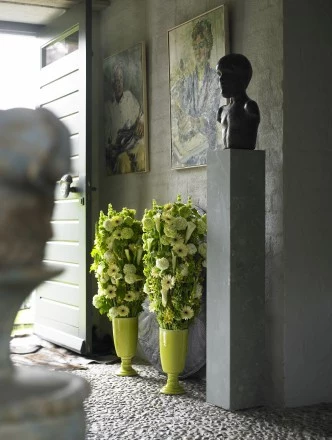 Styl klasyczny. Molucella, kalina, śniedek, mini gerbera oraz cantedeskia. Te dwie kolumny kwiatów nieprzypadkowo zostały umieszczone przy drzwiach frontowych: ta elegancka aranżacja wskazuje na to, że wiosna naprawdę nadeszła i na dobre zadomowiła się. 