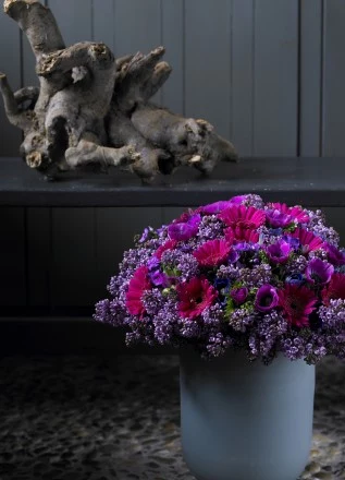 Styl klasyczny. Zawilec, gerbera i bez. Ten ściśle związany okrągły bukiet wygląda perfekcyjnie w klasycznym otoczeniu. Pomimo użycia różnorodnych kwiatów, zabawa odcieniami jednego koloru powoduje, że bukiet jest bardzo stylowy. 