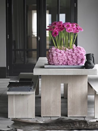 Styl nowoczesny. Gerbera i hiacynt. W otoczeniu mocnych i surowych materiałów, gerbera osadzona w różowej chmurce z hiacyntów zadziwia swoim pięknem. Mimo, że gerberę charakteryzują proste linie, hiacynt dodał kompozycji miękkości i puszystości. 