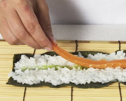 Na ryżu rozprowadź pasek wasabi. Kolejne paski ułóż z ogórka i łososia.