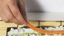 Na ryżu rozprowadź pasek wasabi. Kolejne paski ułóż z ogórka i łososia.