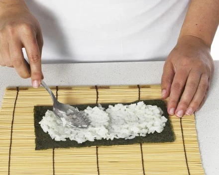 Ryż równomiernie rozprowadź na nori tak, aby zostawić odstęp 1 cm od dołu i 4 cm od góry.