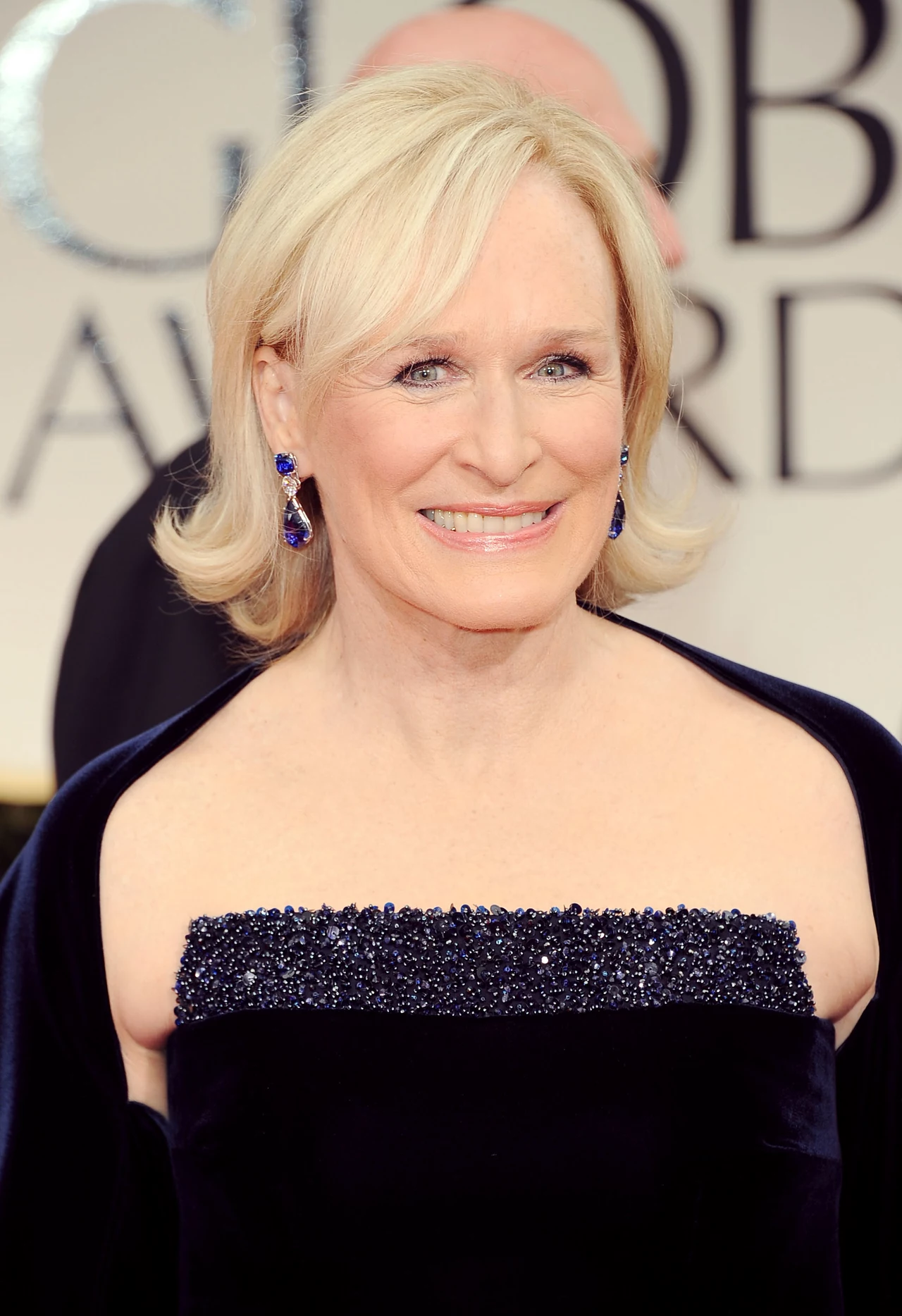 Glenn Close z średniej długości włosach, wywiniętych na zewnątrz. Świetne połączeniu szarego odcienia blonu i kolczyków w kolorze szafirowym Glenn Close z średniej długości włosach, wywiniętych na zewnątrz. Świetne połączeniu szarego odcienia blonu i kolczyków w kolorze szafirowym