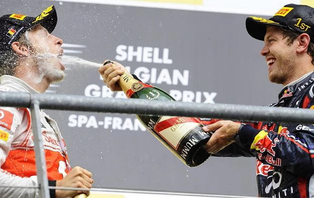 Sebastian Vettel poi Jensona Buttona szampanem na podium GP Belgii