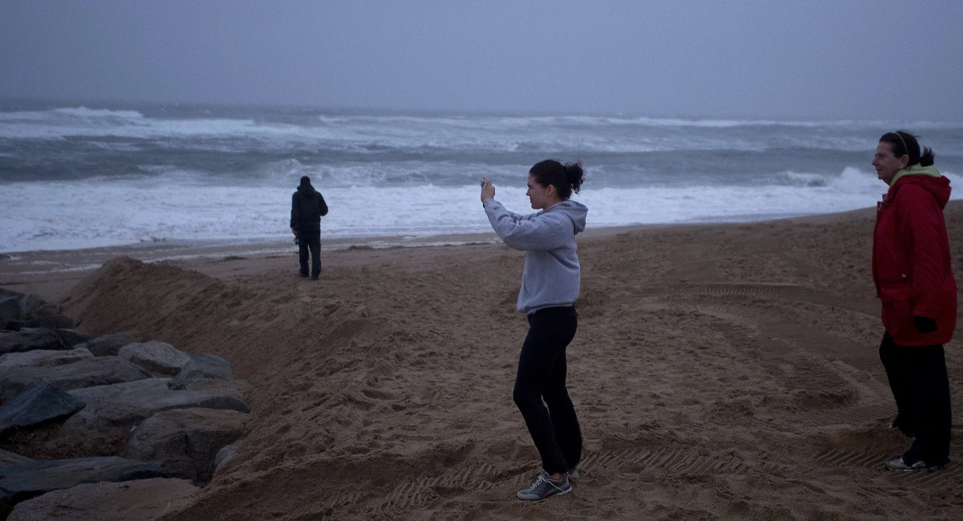 Kobieta robiąca zdjęcie niespokojnemu oceanowi