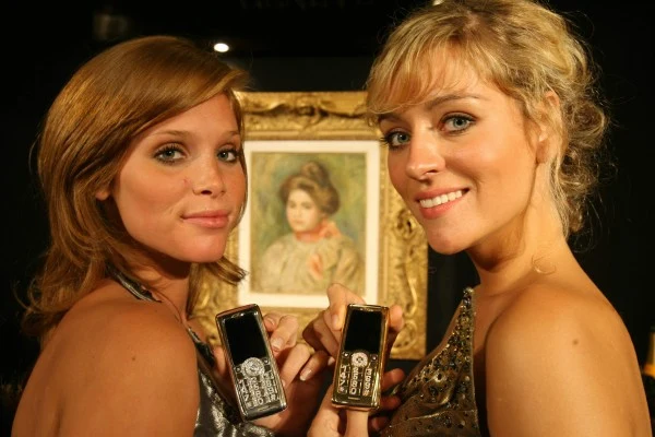 Impreza lifestylowa w Cannes - dwie modelki prezentują pozłacane telefony komórkowe.