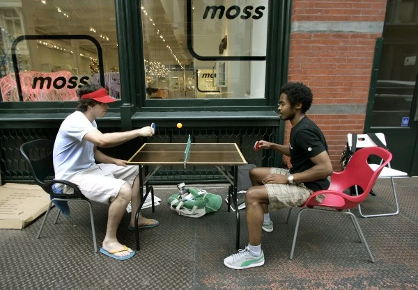 Dwóch przyszłych posiadaczy iPhone relaksuje się przy partyjce ping-ponga w oczekiwaniu na otwarcie sklepu.