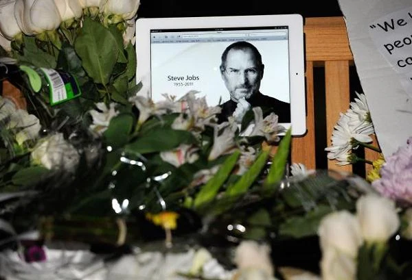 Kwiaty oraz Ipad ze zdjęciem Steve'a Jobsa umieszczone na prowizorycznym pomniku przed siedzibą firmy Apple.
