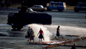 Armatka wodna przepędza starsze kobiety od krzyża z kwiatów na placu Zwycięstwa w Warszawie