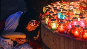 Starsza kobieta z bochenkiem chleba przy zniczach zapalonych z okazji Dnia Pamięci. Kijów