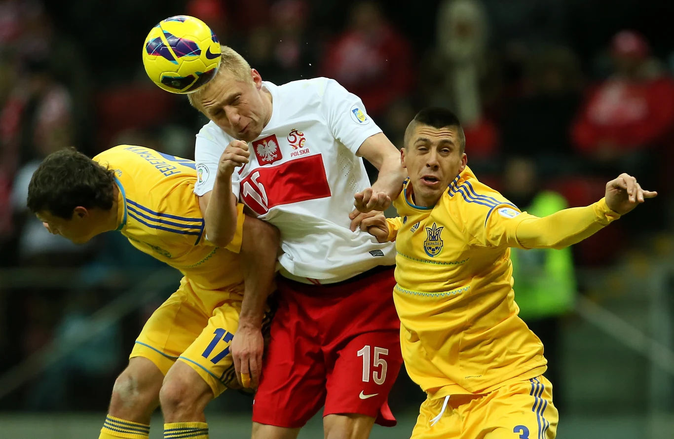 Ukraińcy Artem Fedecki (L) i Jewhen Czaczeridi (P) walczą o piłkę z Polakiem Kamilem Glikiem 