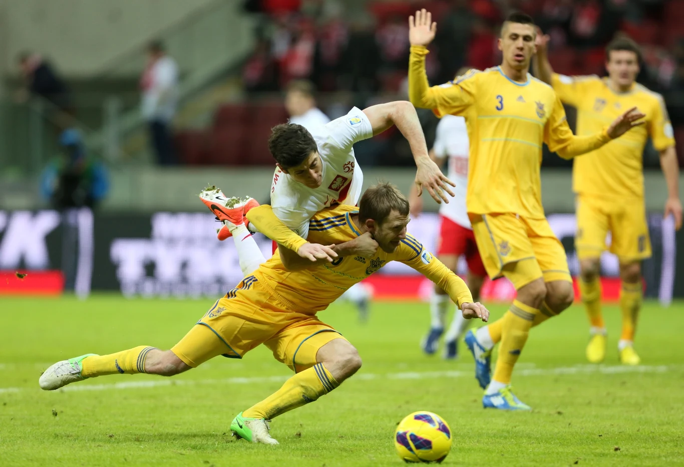 Ukrainiec Ołeksandr Kuczer (niżej) walczy o piłkę z Robertem Lewandowskim 