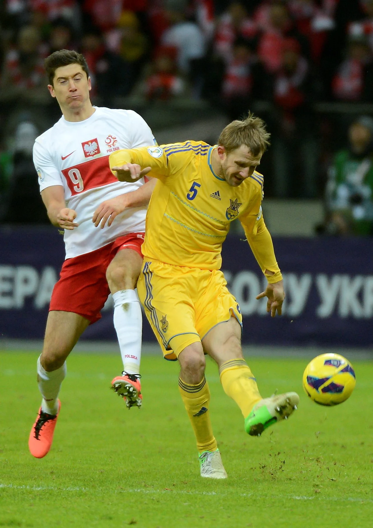 Ukrainiec Ołeksandr Kuczer (P) walczy o piłkę z Polakiem Robertem Lewandowskim 
