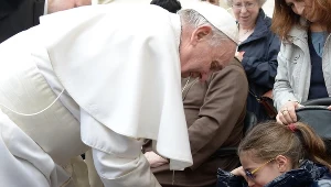 Papież Franciszek składa podpis na gipsie