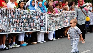 Chłopiec przechodzący obok transparentu ze zdjęciami ofiar masakry